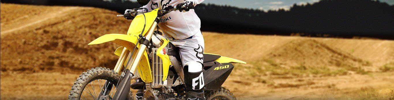 Close-Up of a man on a yellow Suzuki motorcycle riding on a dirt track.